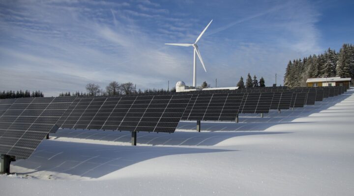 Solar Panels on Snow With Windmill Under Clear Day Sky